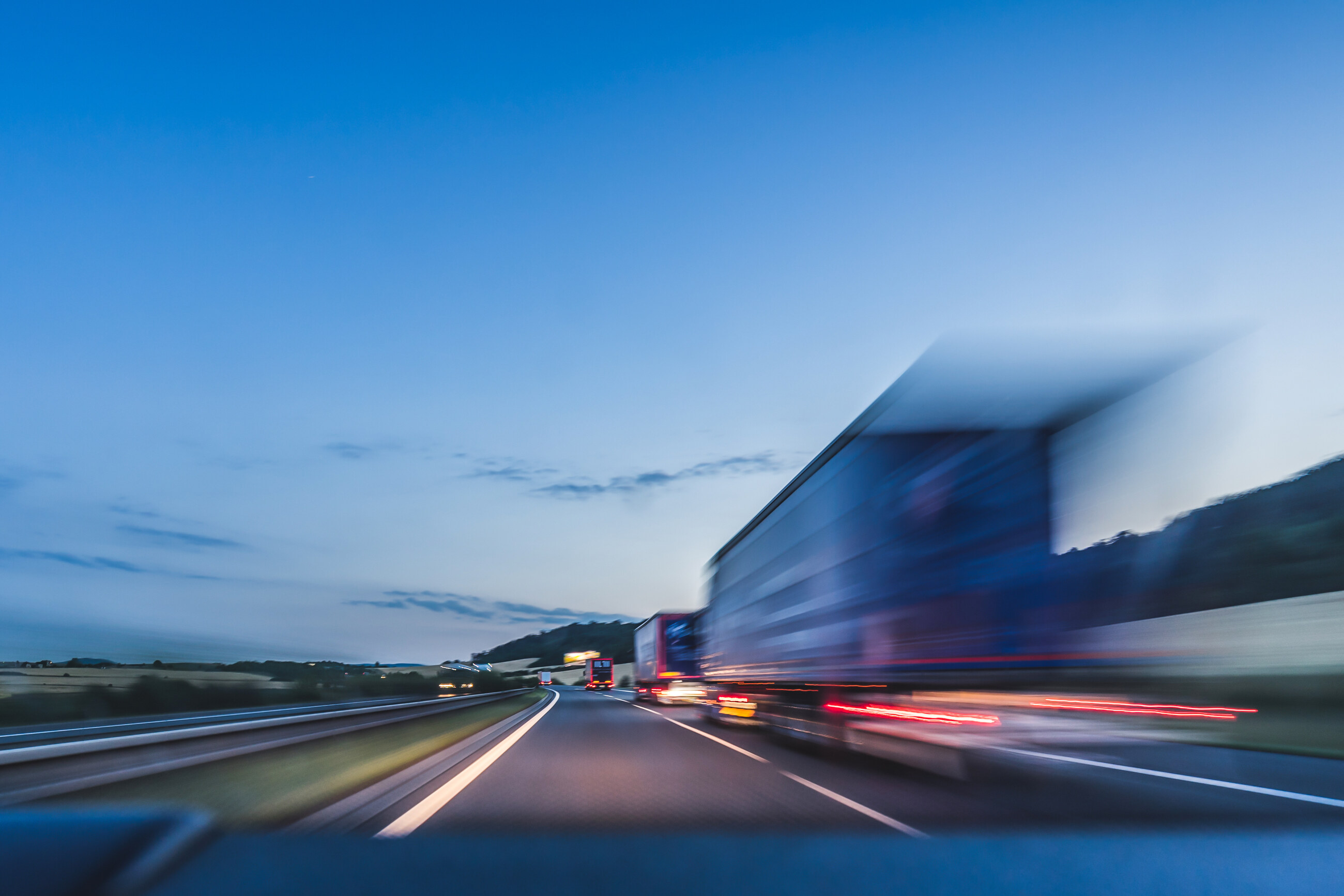 Poids lourd filant sur une autoroute au crépuscule, effet de vitesse